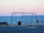 A beach sunset behind a metal swingset